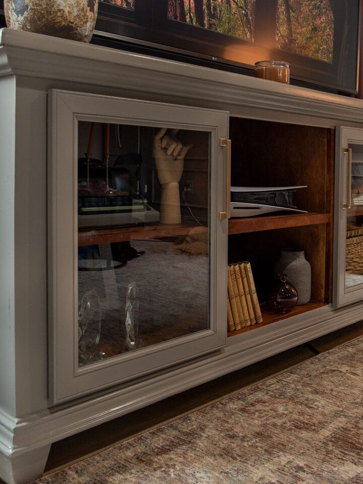 A styled media console with a dark academia decor and painted furniture mood.