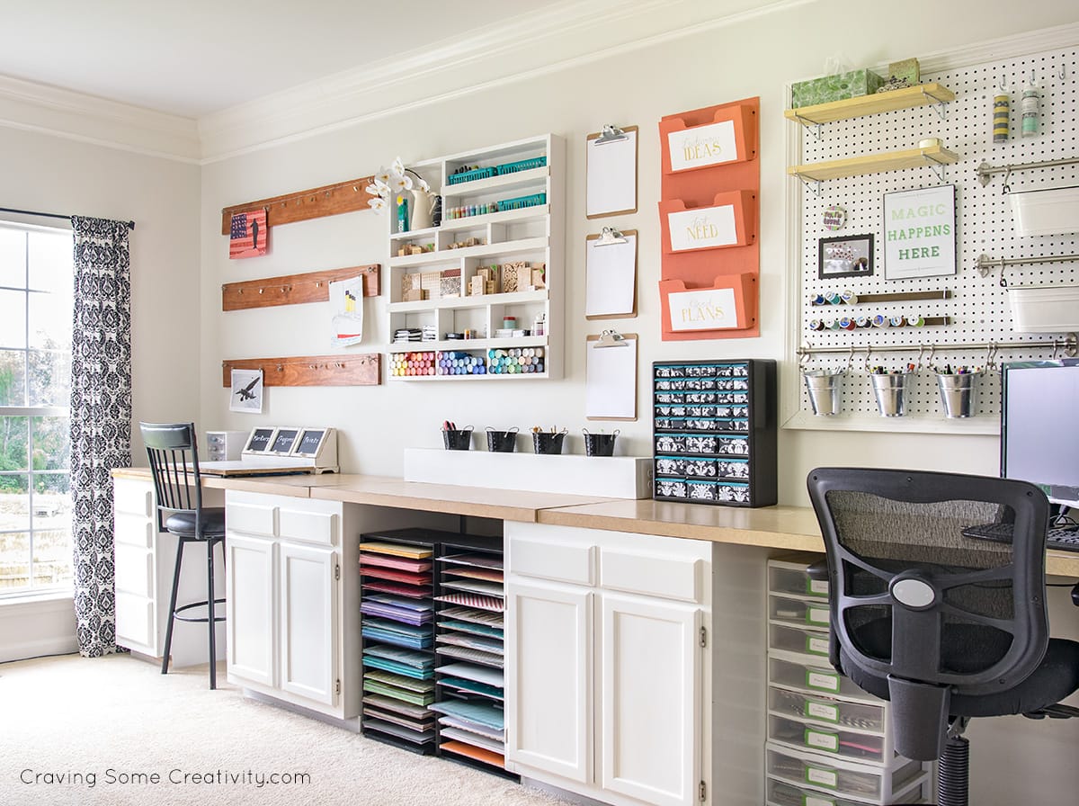 Craft room organization with colorful supplies on the walls and a row of cabinets for storage.