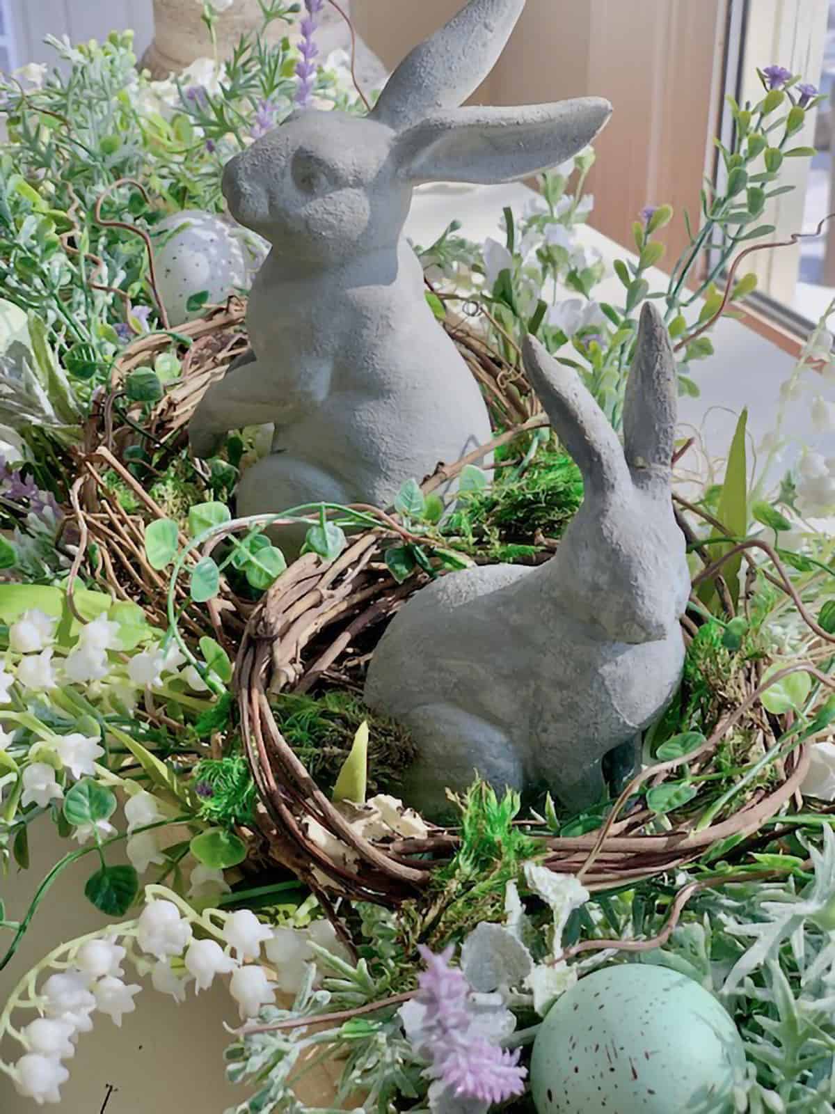 Closeup of two concrete bunnies in a nest centerpiece for spring or easter table decoration.