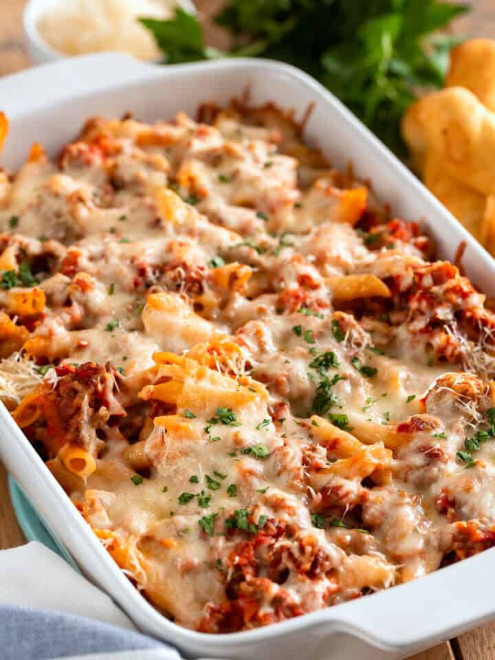 A casserole pan of sausage and penne pasta in a red sauce with melted mozzarella cheese on top.