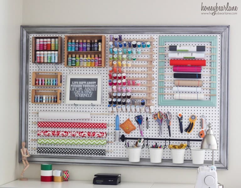 White pegboard on an office wall with craft supplies organized in it perfect for organizing your craft room easily and efficiently.