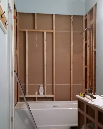 A bathroom remodel with the walls removed to show framing for a large shower niche.