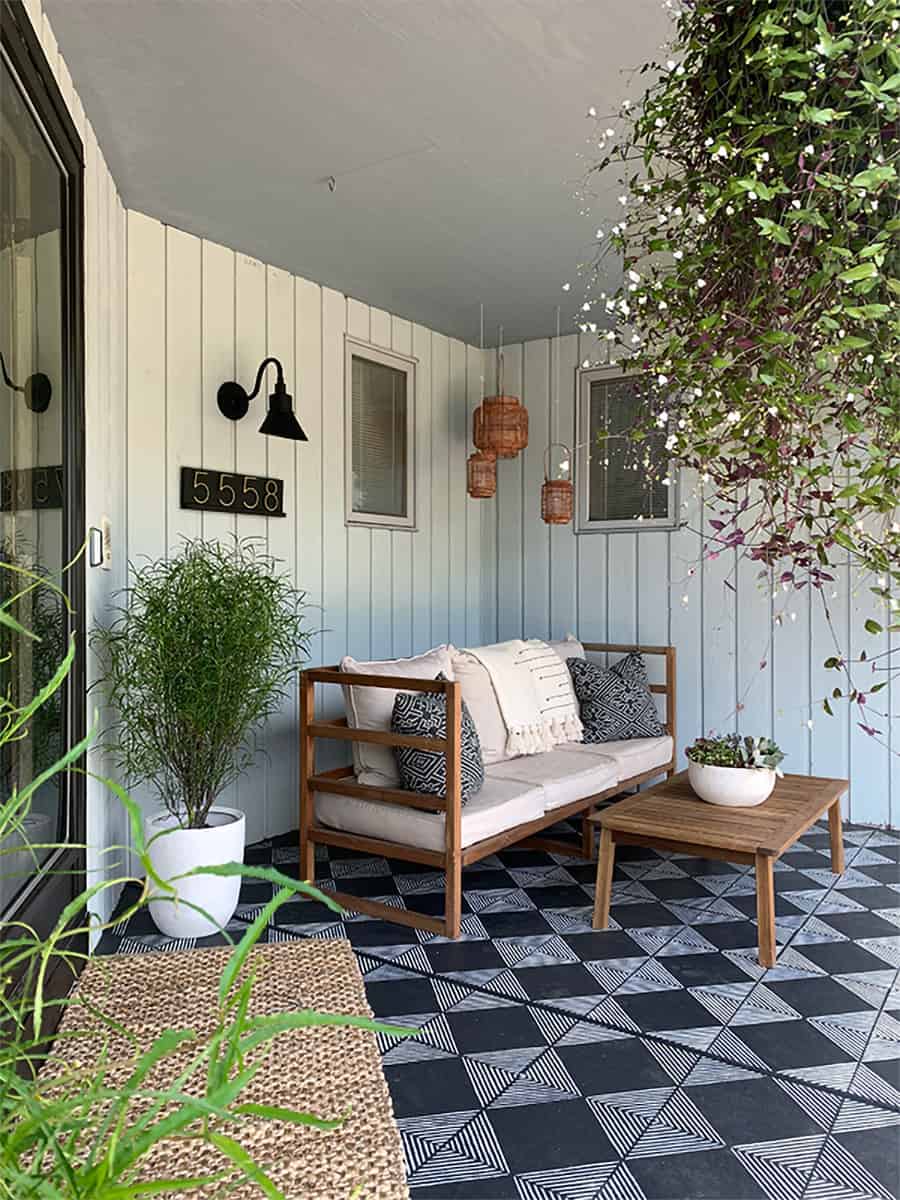 Black and white stenciled concrete porch floor with summer decor and boho accessories