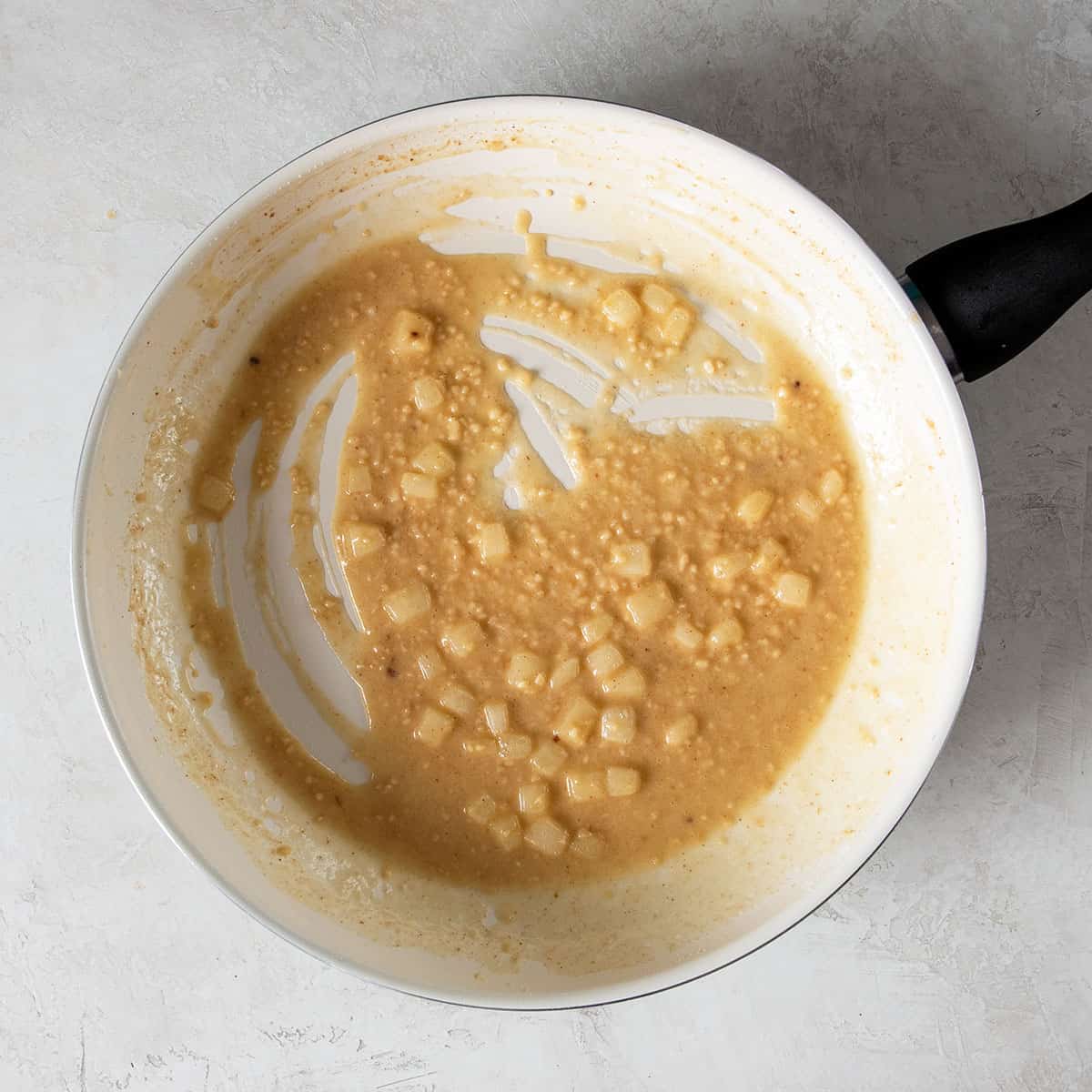 Garlic and onions with a flour roux in a skillet during preparation.