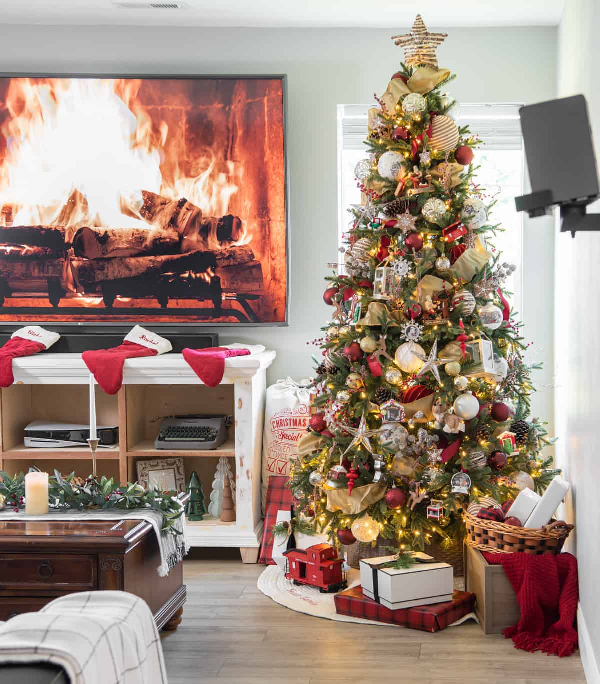 Gingerbread christmas tree in a living room with rustic ornaments, red and gold accents, and a log fireplace on the TV.