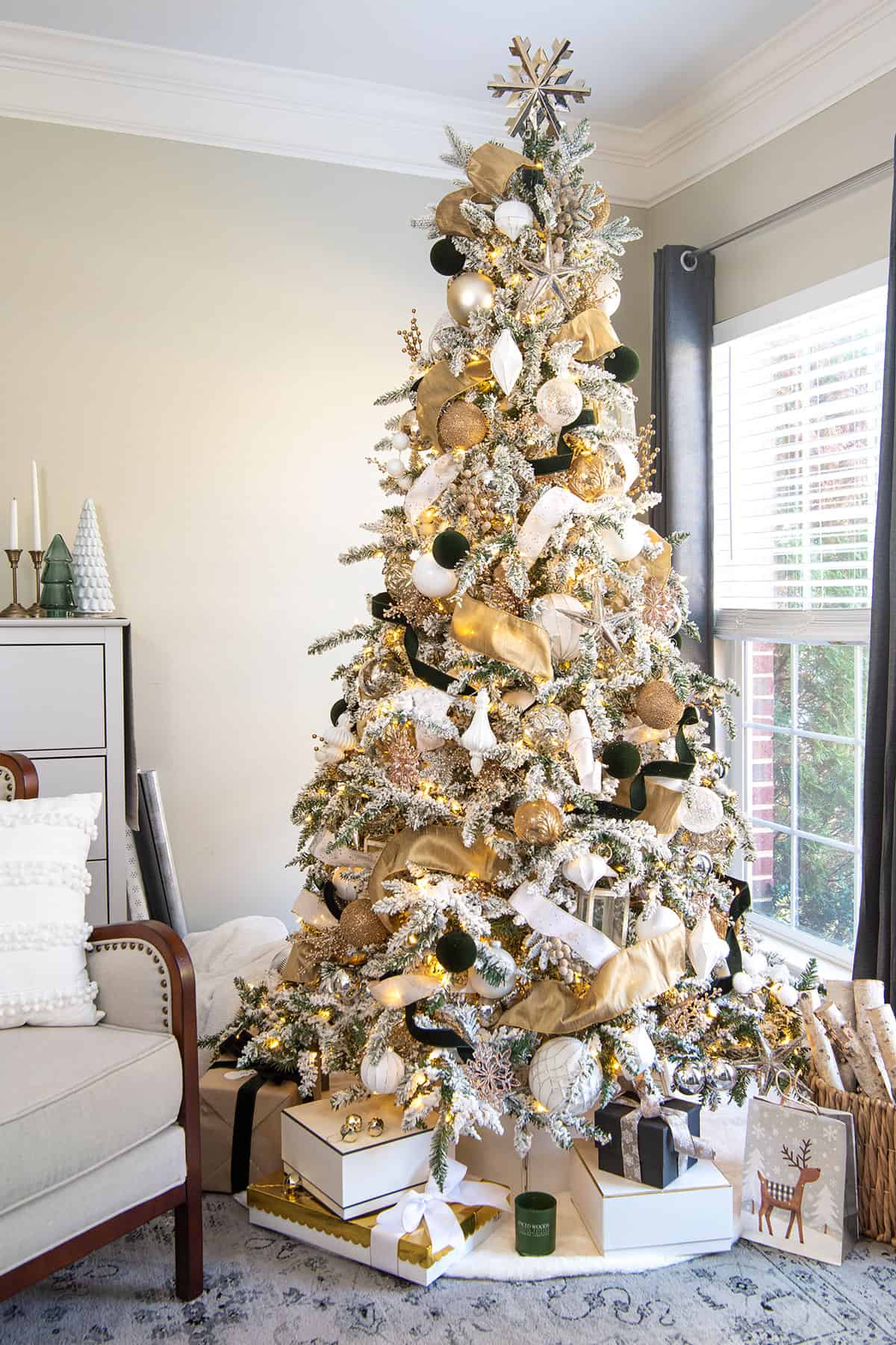White and Gold flocked Christmas tree decorations in a living room with windows.