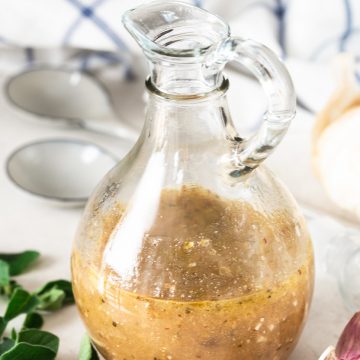 Homemade Greek Salad Dressing in a carafe on a table.