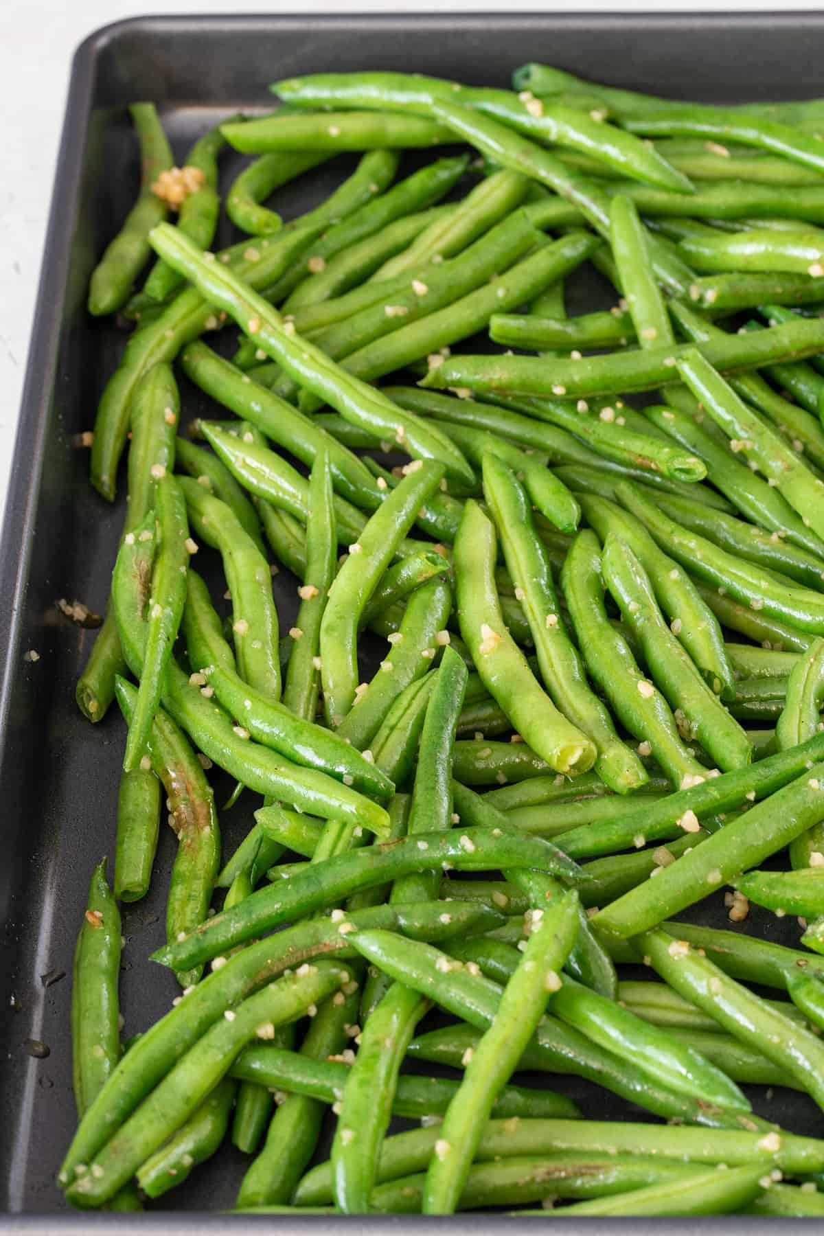 Fresh green beans on a sheet pan ready for oven roasting.