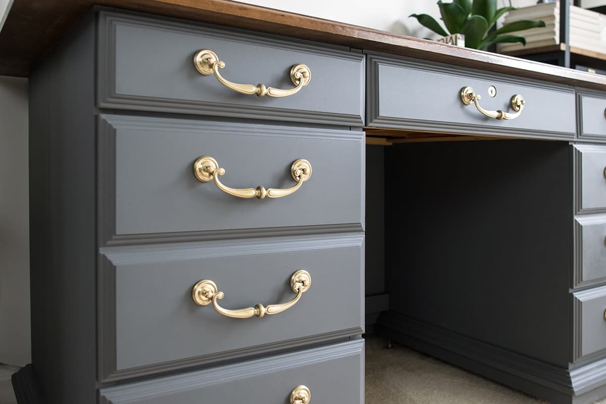 Grey desk with brass hardware with chalky finish paint, sprayed with General Finishes Flat Poly Acrylic top coat.