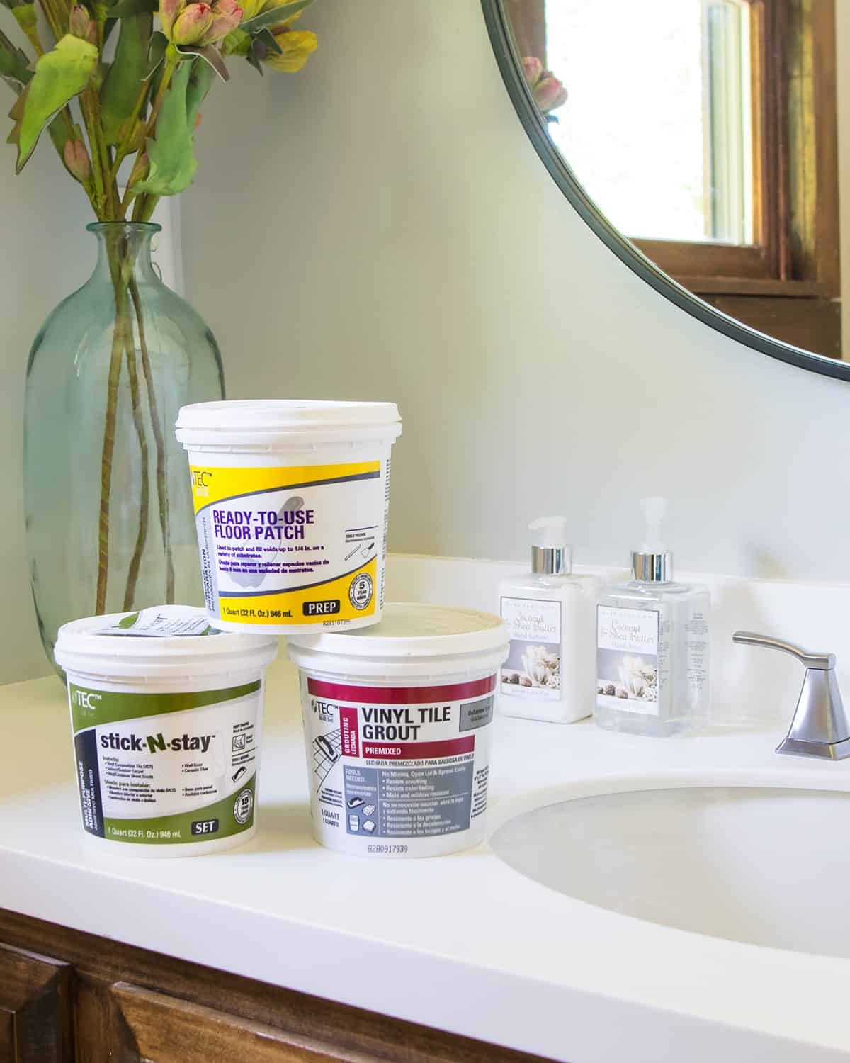 Tubs of vinyl tile grout, ready to use floor patch and stick and stay on bathroom countertop.