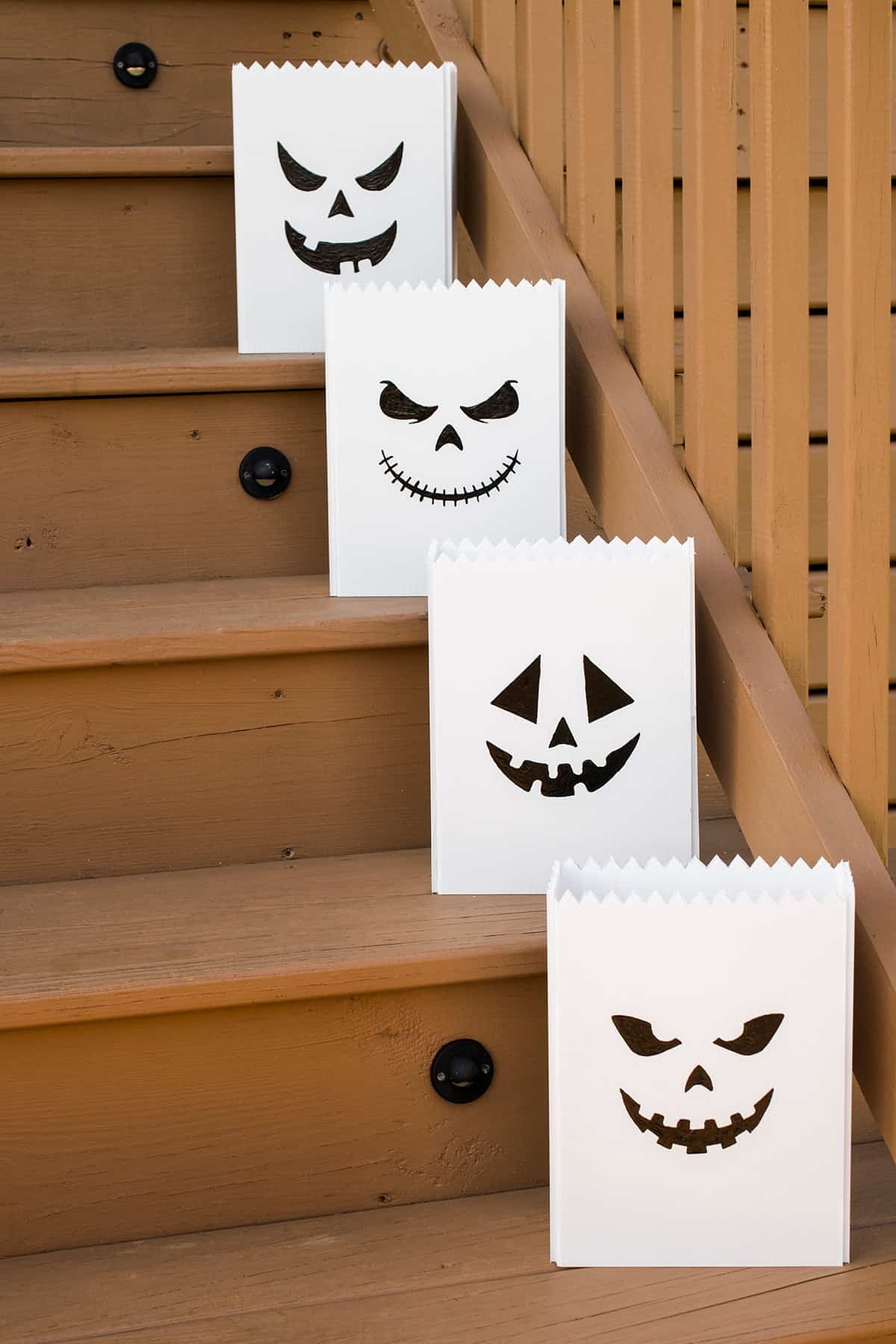 Outdoor lighted jack-o'-lantern luminaries sitting on steps.