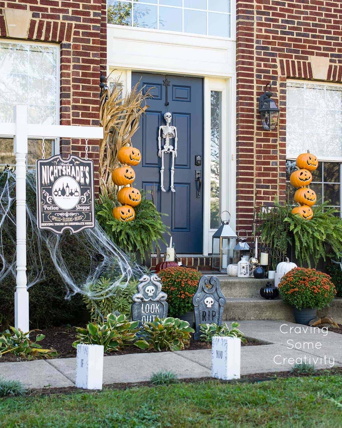 Witch's apothecary front porch Halloween decor with pumpkin topiaries, tombstones, and DIY Decorations.