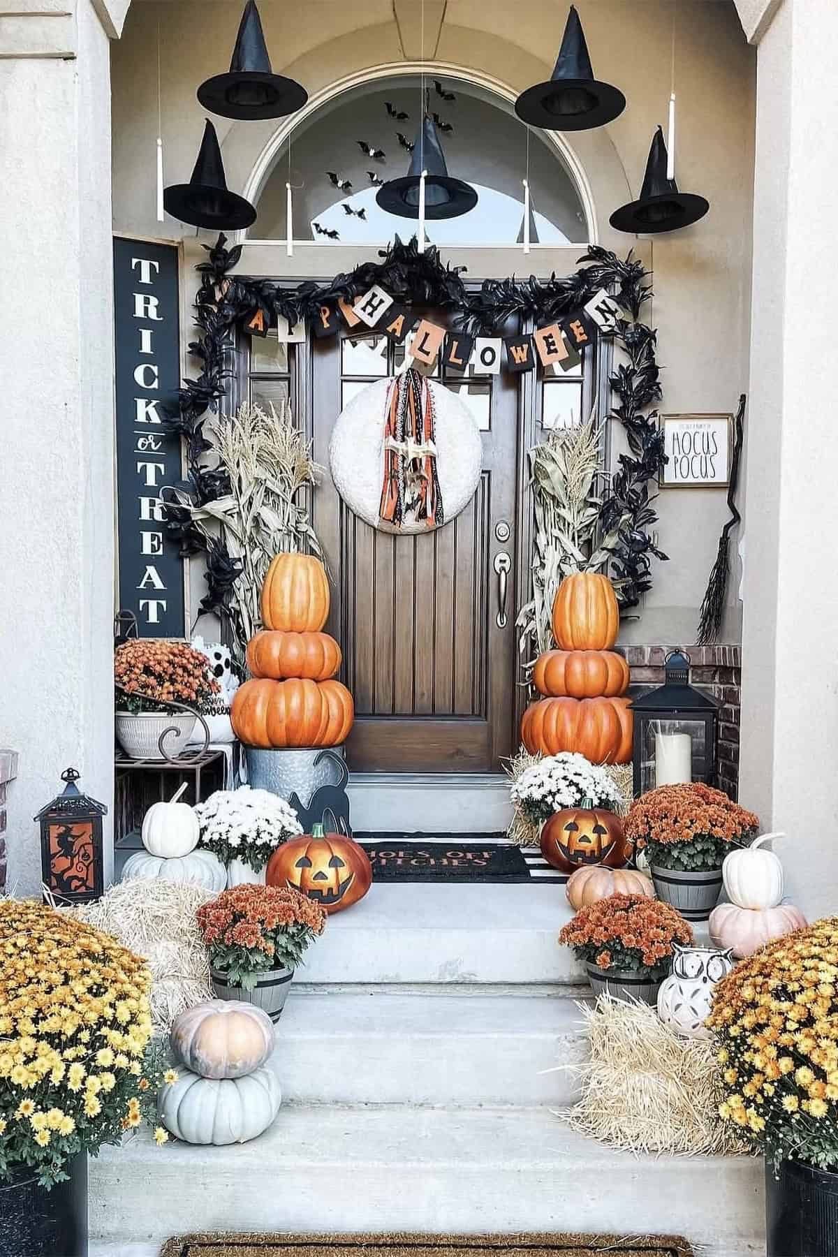 Halloween Porch with witch hats and stacked pumpkins and mums.