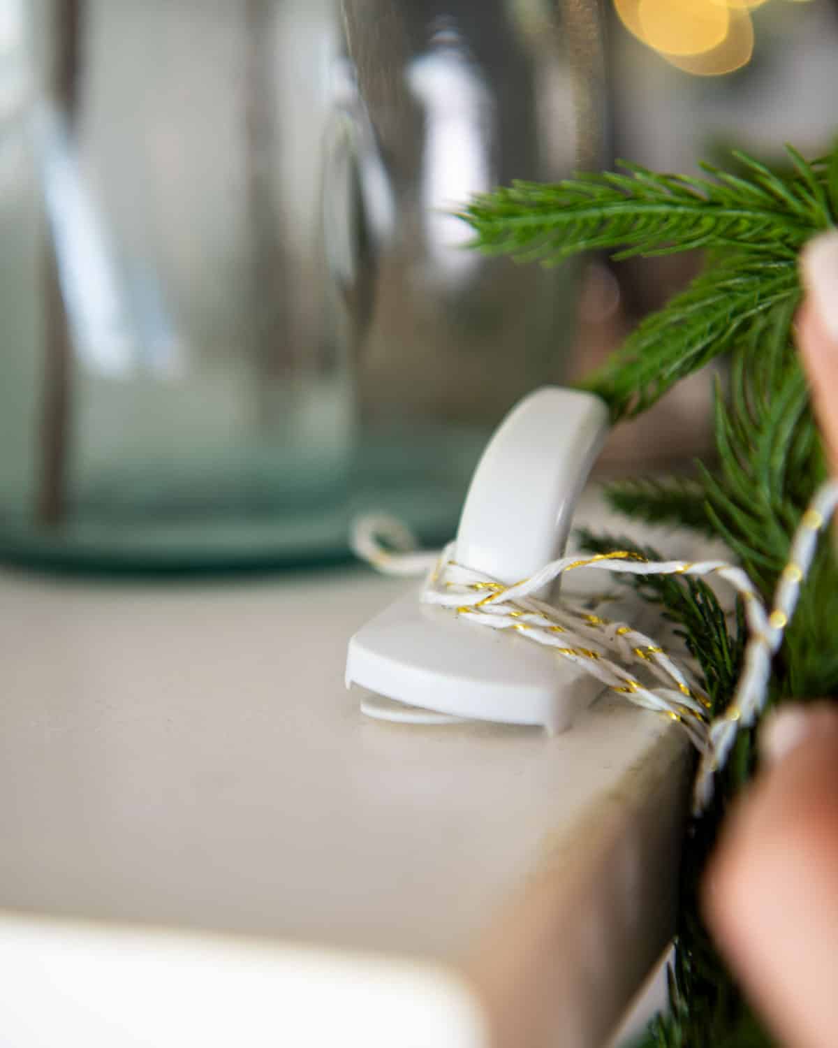 Closeup of an extra-large command hook holding a pine swag up with twine.
