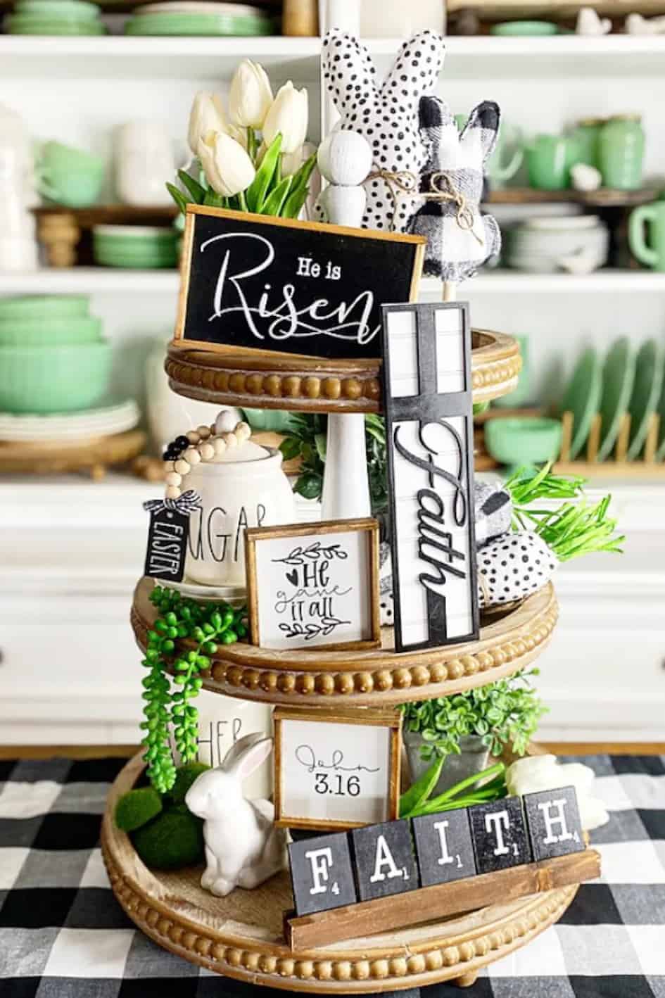 Tiered tray centerpiece filled with Christian and He is risen signs and decorations for Easter or Spring.