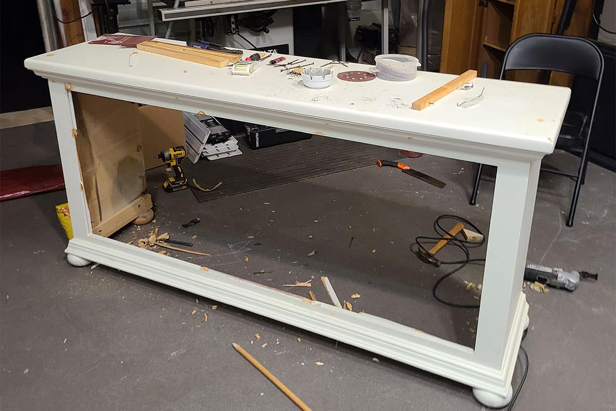A gutted white dresser with the drawers and back removed.
