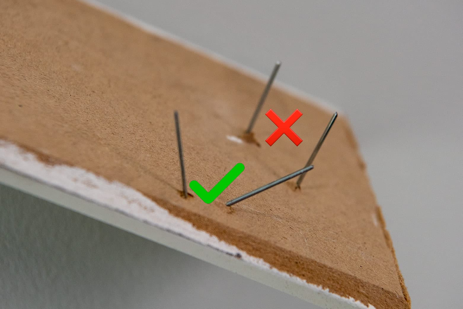 A trim moulding board with brad nails in it, one set straight and one set at opposing angles.