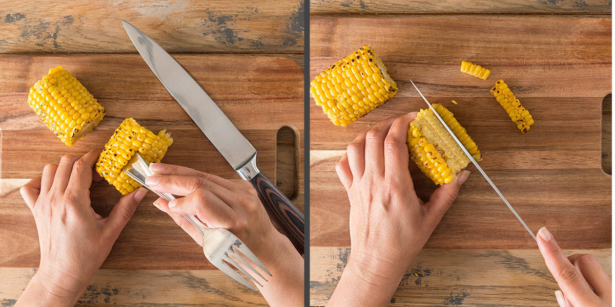 Demonstration of how to cut corn kernels off a cob easily using a knife and the back of a spoon.