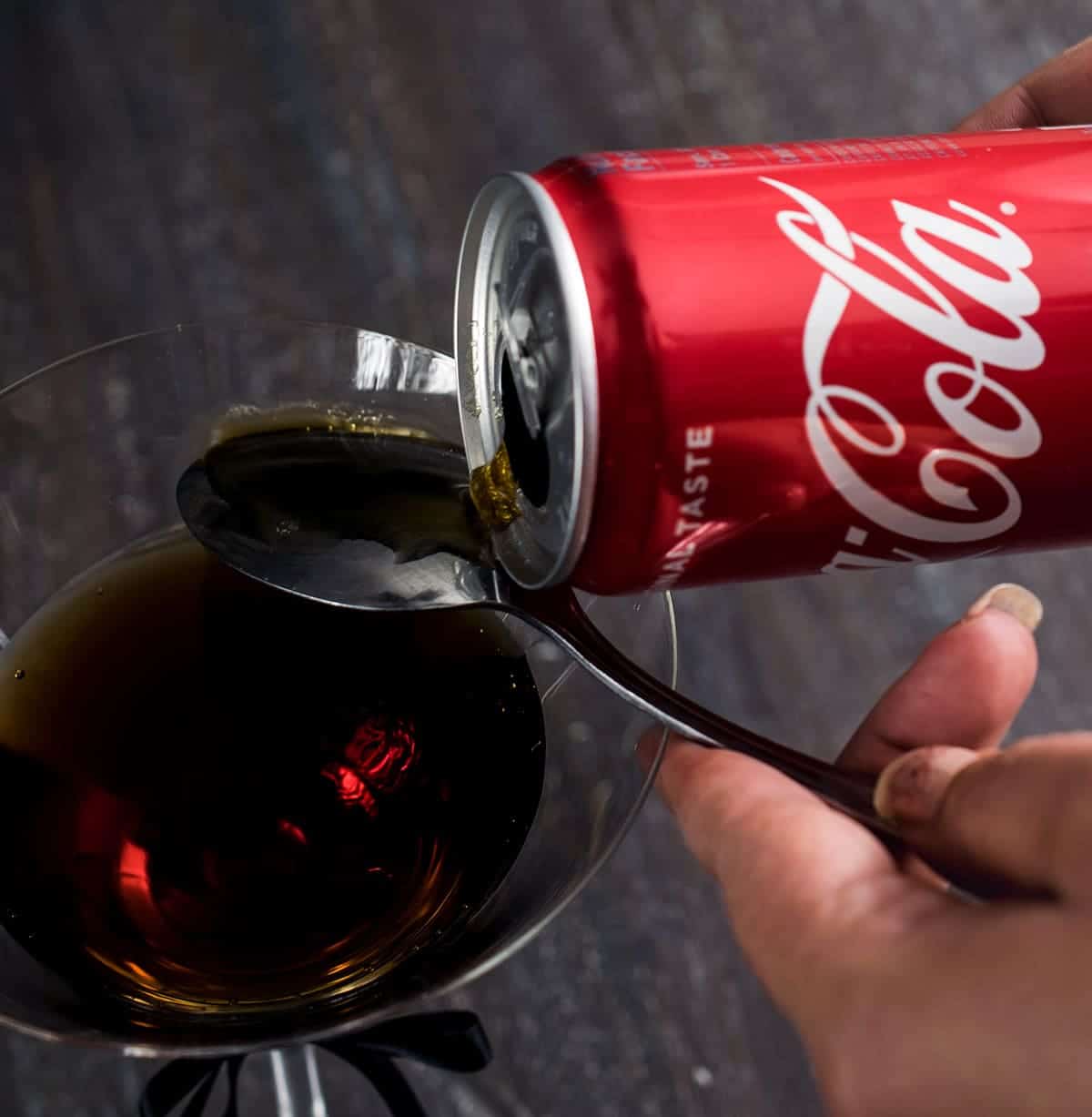 Using a spoon to make a layered mixed drink cocktail.