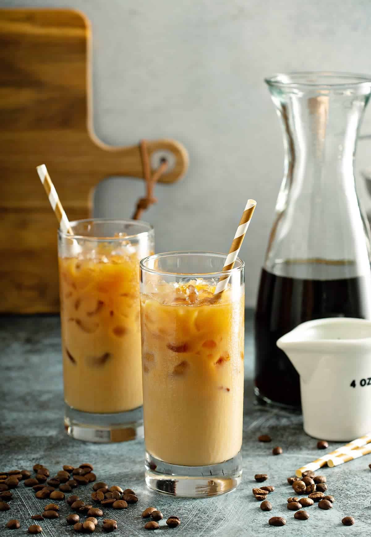 Glasses of Mixed Iced Latte Coffees with carafe and golden straws in the beverages.
