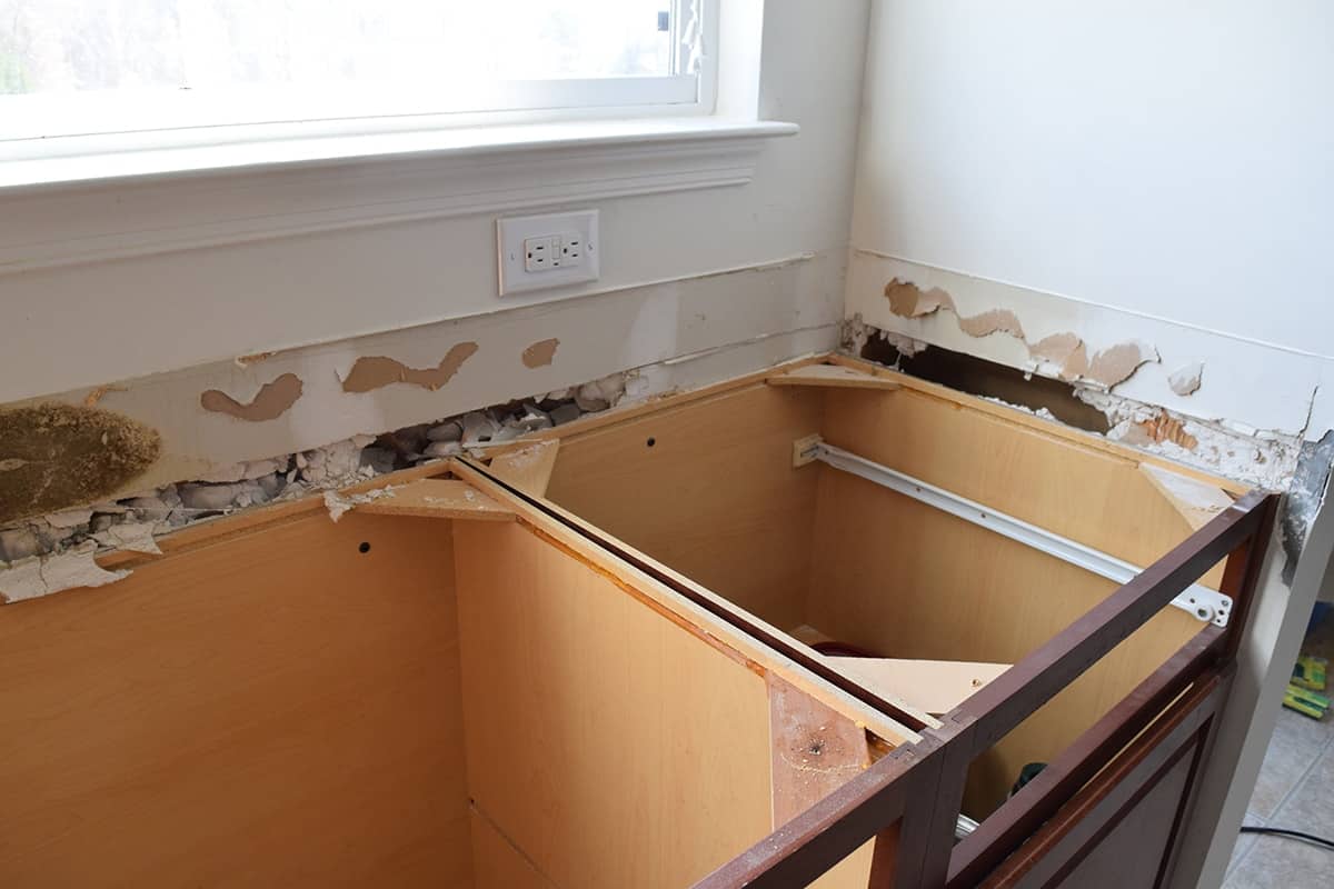 Dark wood cabinets in white kitchen with white walls and countertops removed.
