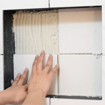 Laying tile in a shower wall niche.