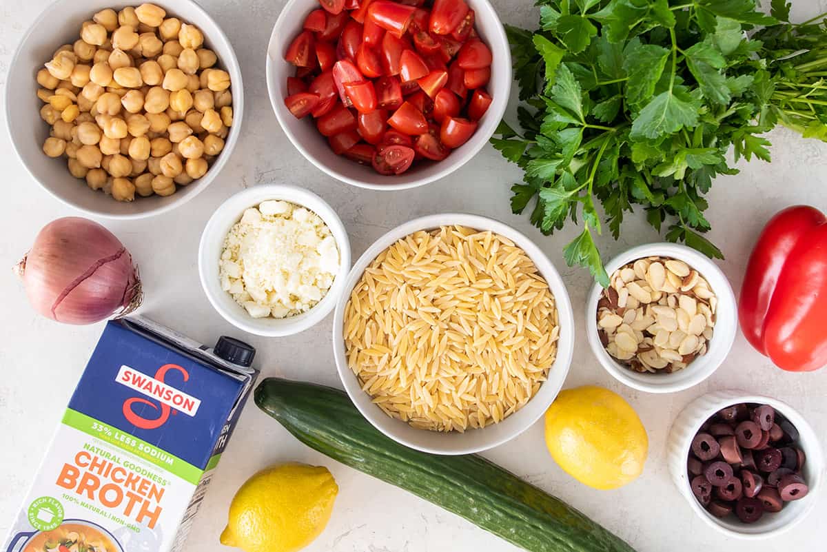Ingredients for Mediterranean pasta salad laid out on a table.