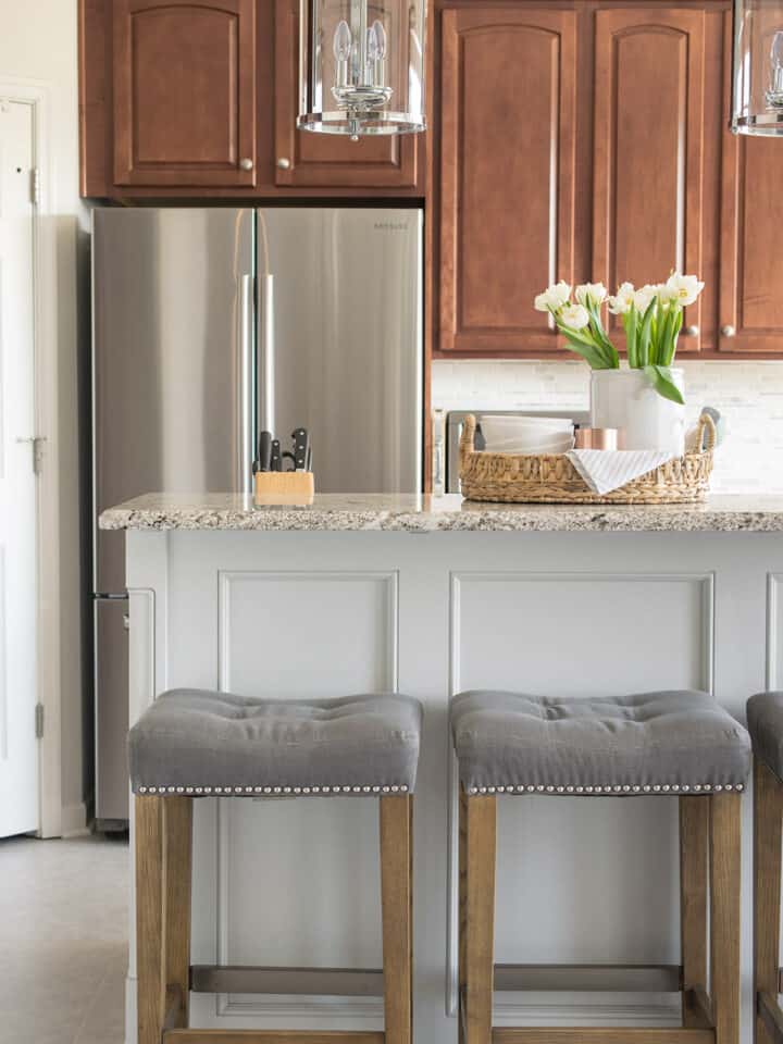 Large grey kitchen island with breakfast bar in traditional trim and two tone different color from the cabinets.