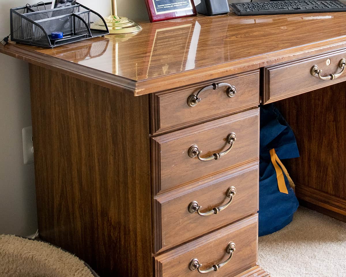 Angled view of an antique wood executive desk with Formica top.