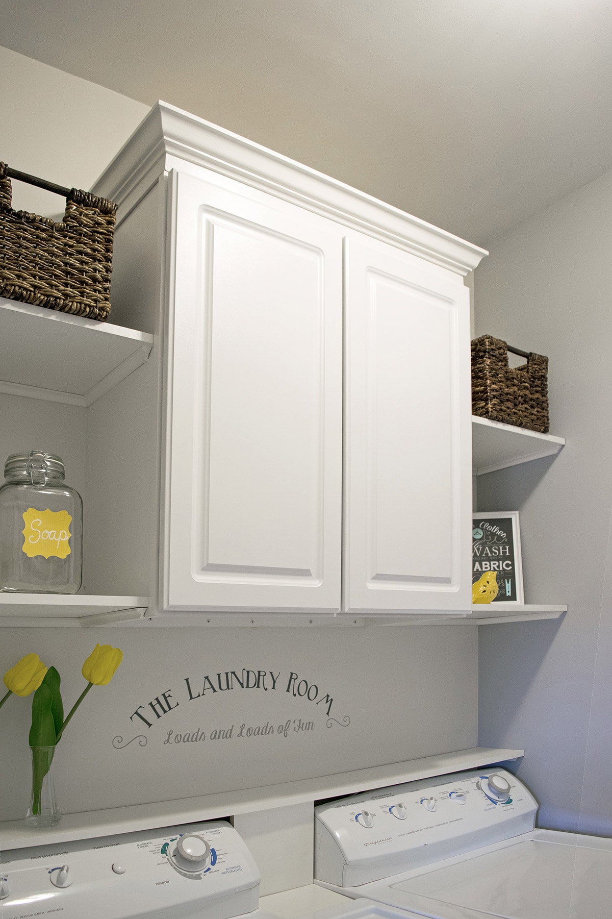 White cabinet in laundry room above washer and dryer.