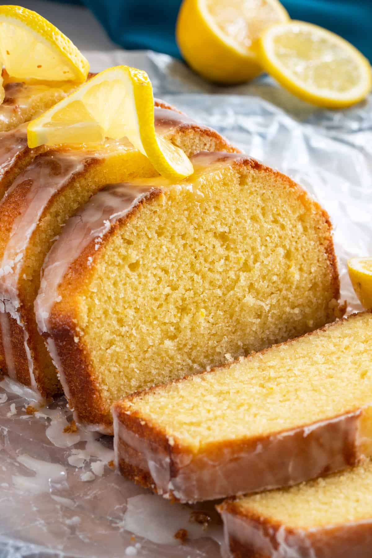 Sliced lemon yogurt cake with glaze and lemon curl slices on top.