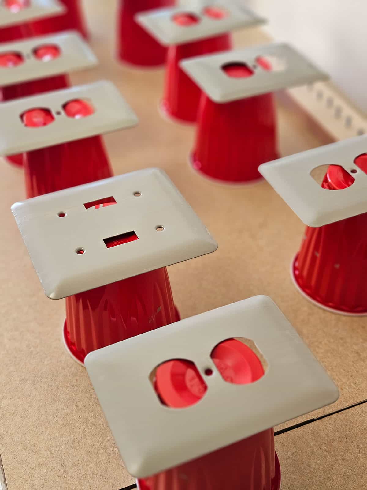 A set of light switches and outlet covers drying after being DIY painted.