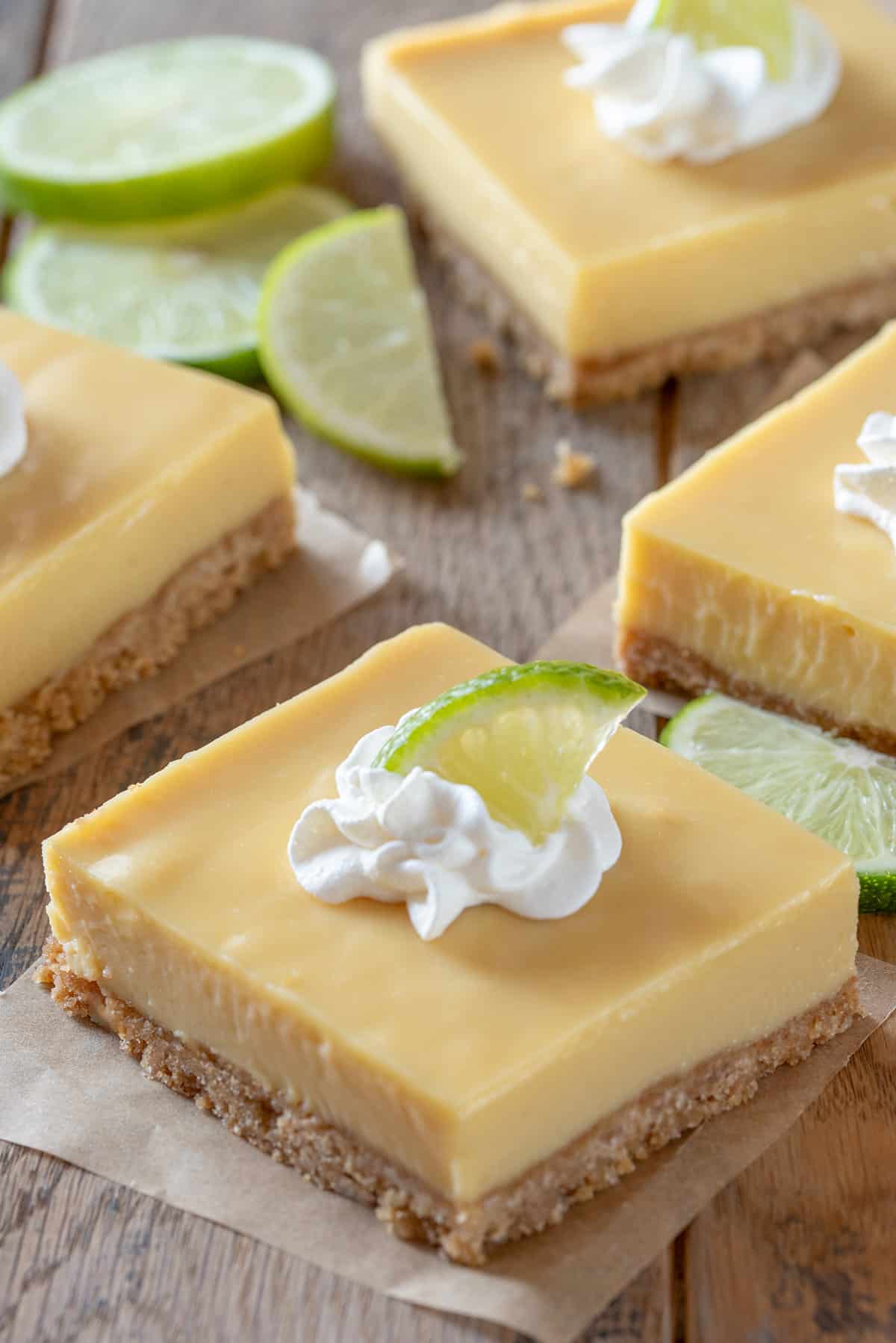 A key lime pie bar with a dollop of whipped cream on top and a lime wedge.