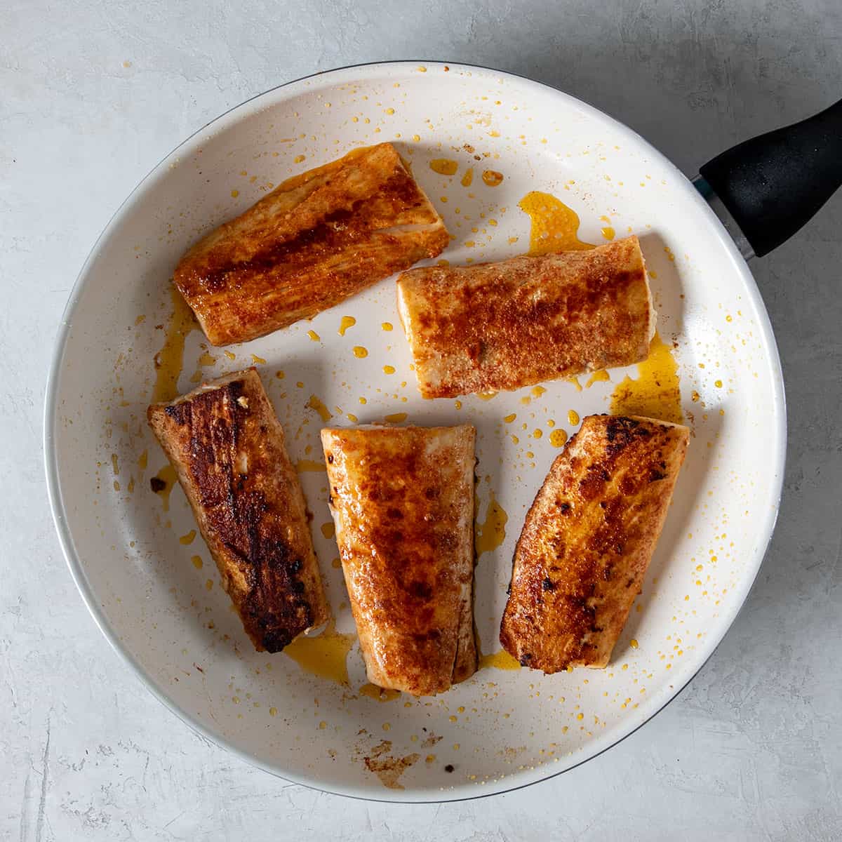 Pan seared mahi-mahi filets laid in a skillet just after finished cooking.
