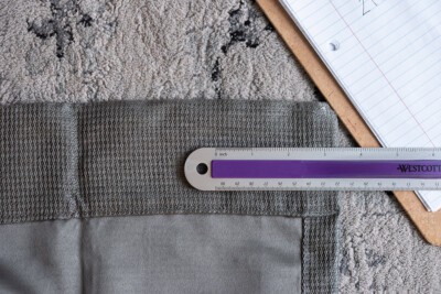 A ruler on top of a curtain to show edge to first grommet measurement.