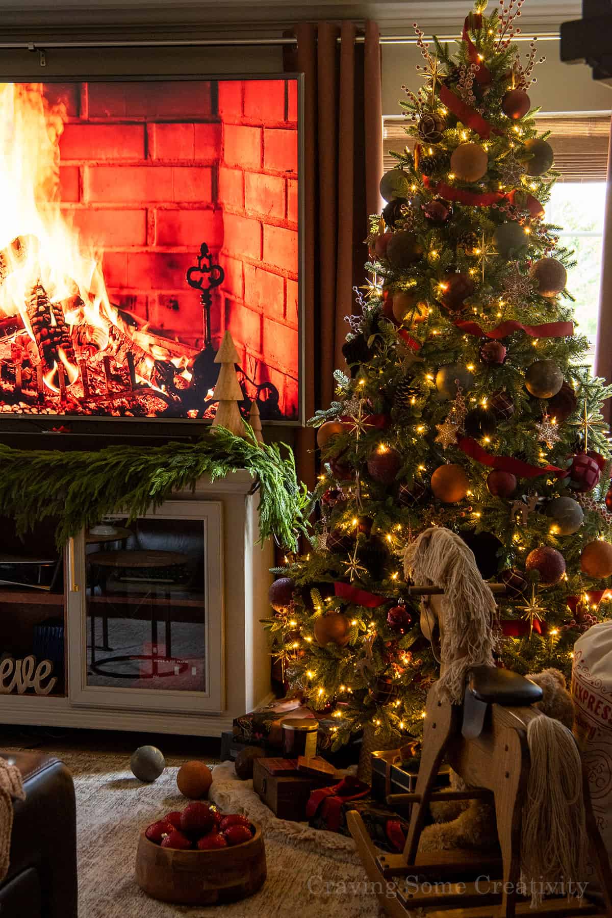 A cozy, dimly lit living room with Christmas tree lights on and a fireplace on the TV.