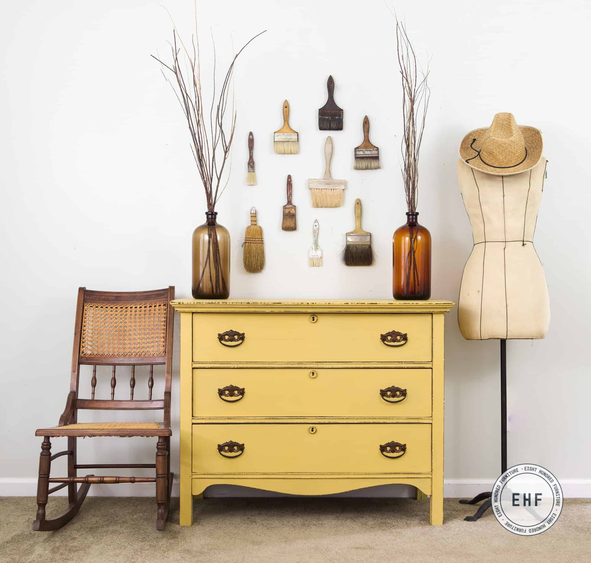 Mustard seed yellow antique dresser with antique rocking chair and empty dress form.