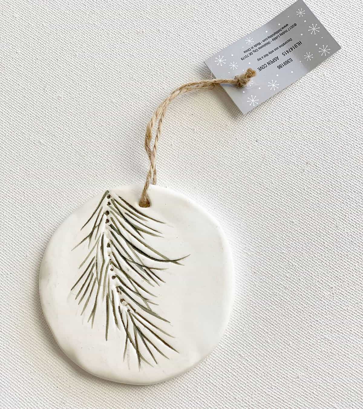 White ceramic polymer clay contemporary evergreen sprig Christmas tree ornament with twine price tag.