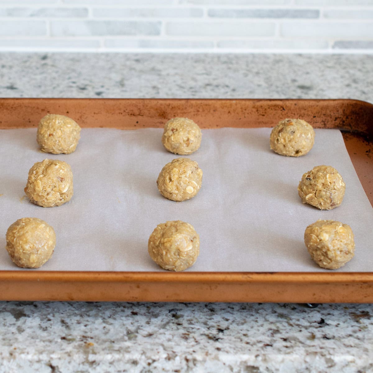 Oat cookie balls on a baking sheet before going into the oven.