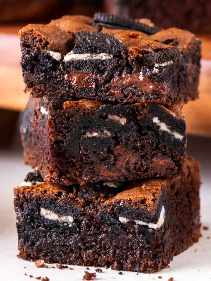 Fudgy Oreo Brownies with chocolate chips stacked high to show texture and oreo bits.