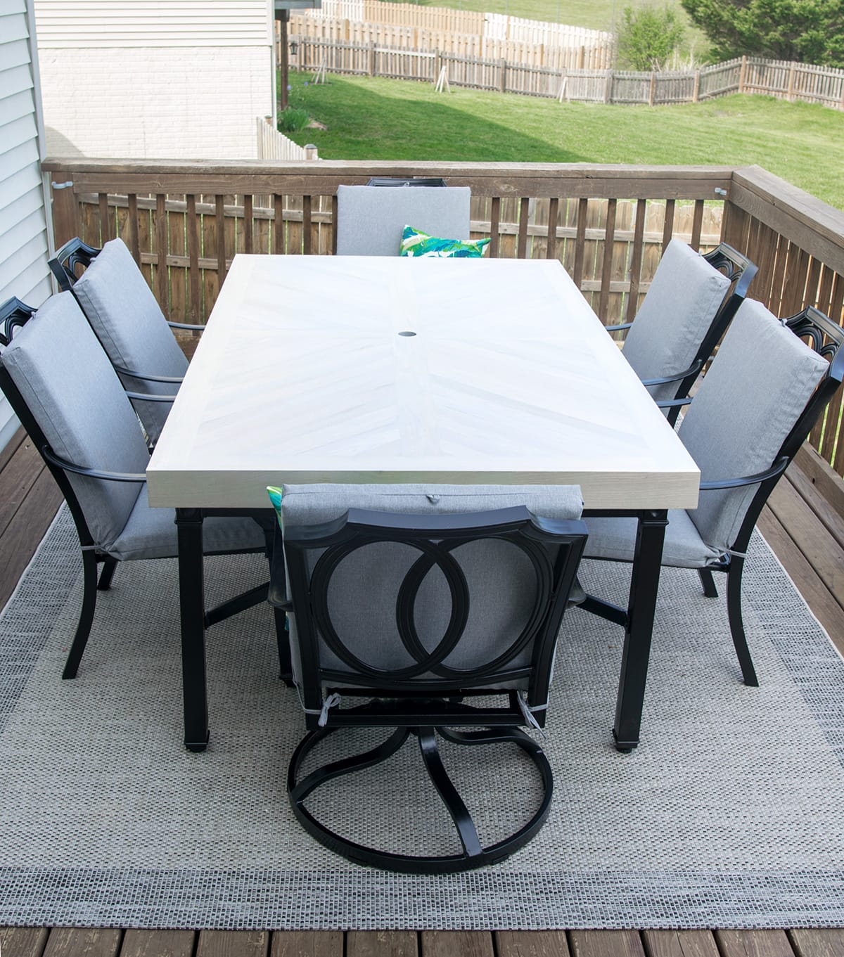 Metal patio table and chairs refinished with black trim, wood top, and gray cushions. 