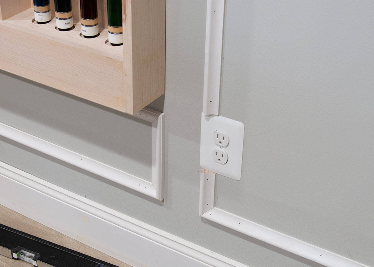 Closeup of an outlet going through a part of picture frame molding and how to fix it.