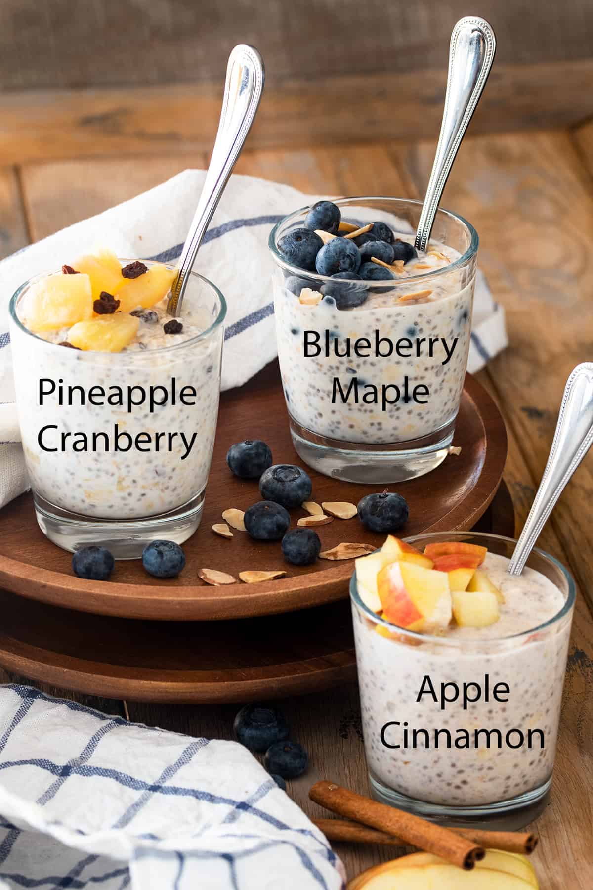 Three mason jars with prepared overnight oats next to assorted fruit on wooden cutting board.