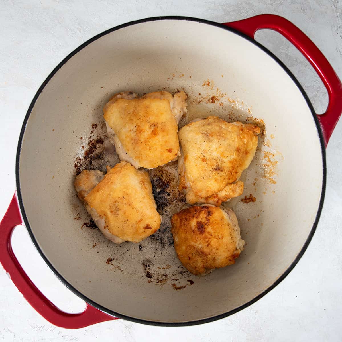 Four bone-in chicken thighs after pan searing for crispy skin.