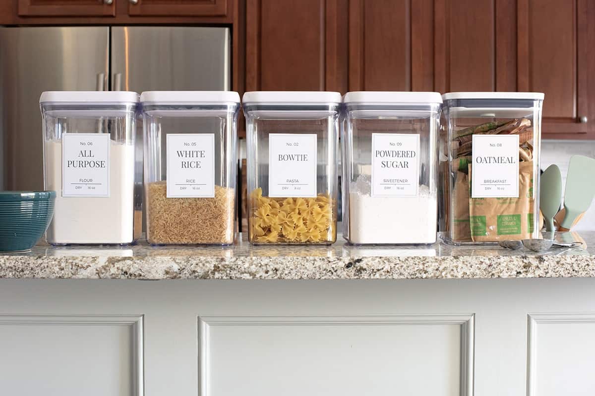Labeled clear canisters lined up neatly on counter top show case contents.