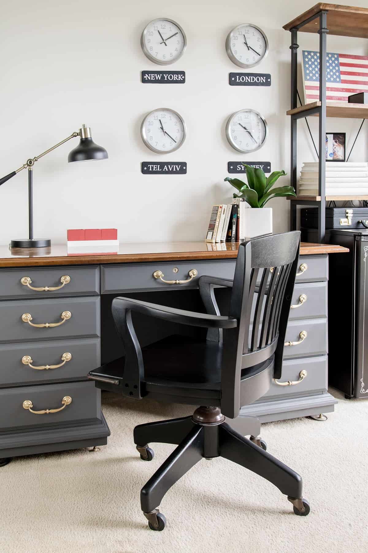 Home office desk and chair painted with soapstone chalk paint or dark gray and brass hardware and black chair.