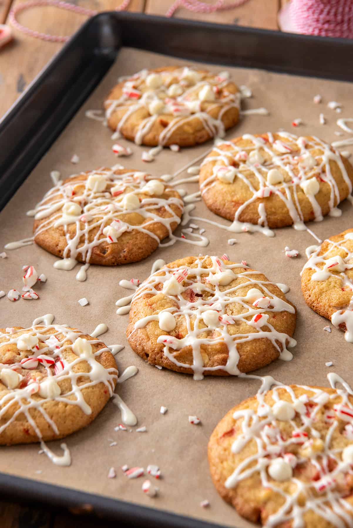 White chocolate cookies on brown wax paper cookie sheet.