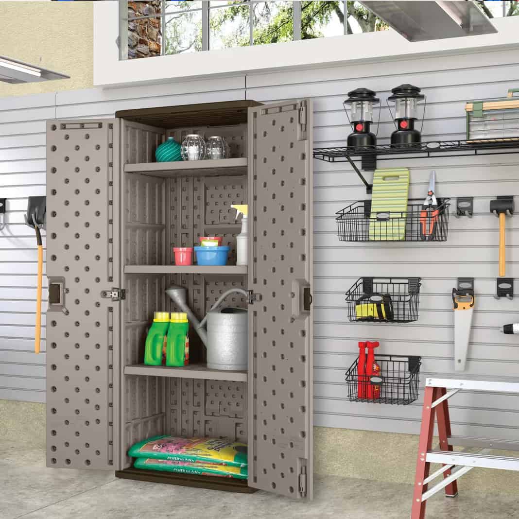 Large plastic cabinet with doors open to show storage shelves in a garage with slat walls for more organization.