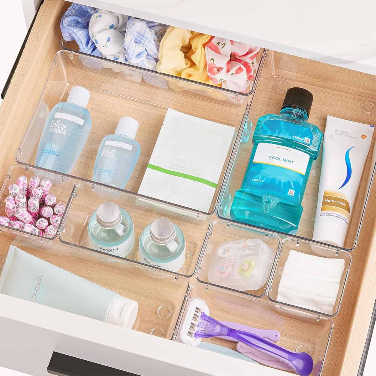 Organized drawer with clear plastic containers to keep toiletries organized.