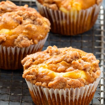Pumpkin muffins with crumb topping on a cooling rack.